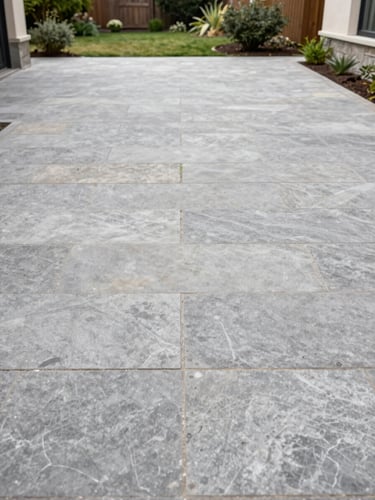 Wide environmental shot of a freshly swept stone patio at a residential property, overcast daylight revealing clean surface texture, no people, garden border neatly edged in the background, documentary framing
