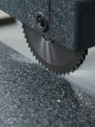 Extreme close-up of a diamond-wire blade slicing through dark gray granite, high-pressure water jets spraying, cold overcast workshop lighting, sharp focus on cut edge.