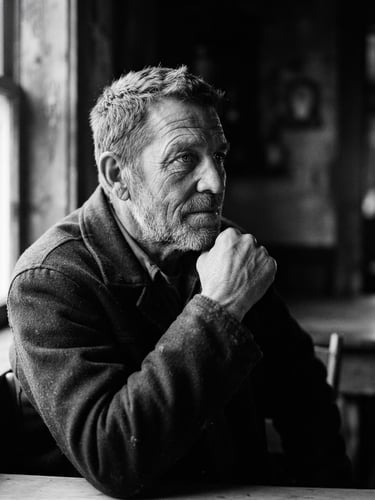 Cinematic black and white portrait of a person looking thoughtfully off-camera, dramatic natural side-lighting, deep shadows, visible film grain, 35mm aesthetic.
