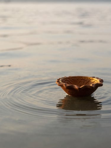 Softly focused flowing water of the Ganges river at dawn with a floating clay diya