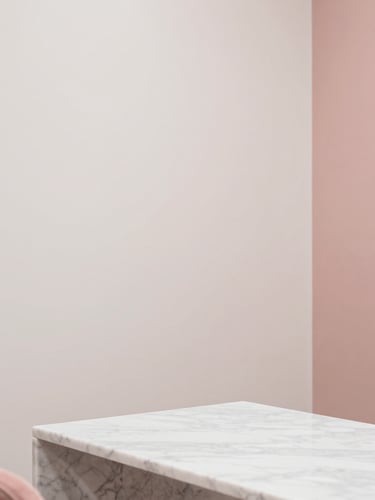 Minimalist interior corner of a luxurious nail salon in Antwerp, soft warm-white walls, dusty rose accents, clean marble table, serene atmosphere