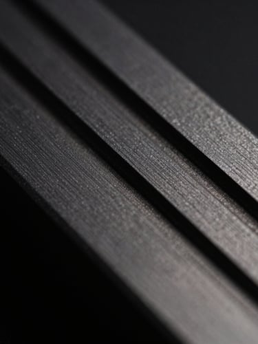 Macro close-up of machined anodized aluminum grooves, dark charcoal metal texture, sharp technical lines, dramatic side lighting, low-key shadows.