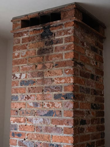 Close-up interior flue photograph of the same brick chimney after cleaning, walls visibly clear, natural brick texture restored, ambient daylight from above, no people