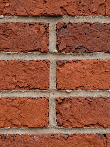 Macro close-up of weathered historic red brick with freshly struck, perfectly matched lime mortar joints, overcast natural light emphasizing texture