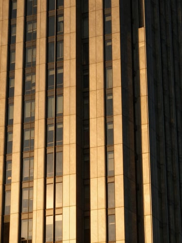Crisp architectural detail of a modern metropolitan skyscraper reflecting rich golden hour light against a deep obsidian sky, premium editorial photography, medium format film.