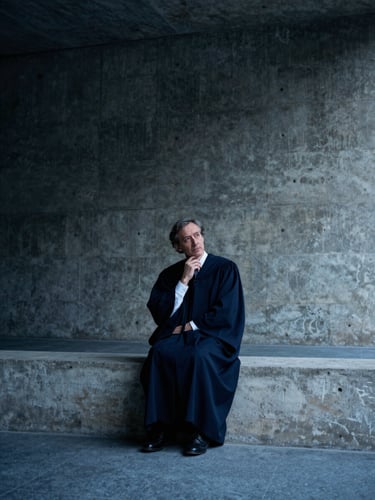 Low-key dramatic portrait of a scholar in thought, cool blue tones, stark shadows, architectural concrete background