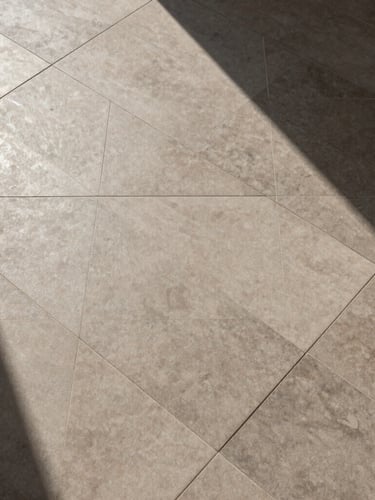 Precise top-down geometric pattern of installed architectural-grade porcelain tiles, high-contrast sun and shadow, deep earth tones, 35mm