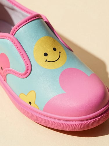 Close-up macro of a quirky retro shoe with vibrant patterns on a cream surface, warm direct studio lighting with sharp shadows, 35mm