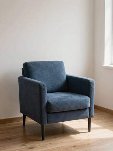 Minimalist clinical editorial photography, a single empty armchair in a quiet consulting room, soft natural window light casting gentle shadows on a wooden floor, muted deep blue and warm off-white tones, shallow depth of field.