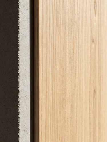 Macro detail shot of architectural materials, raw concrete texture meeting perfectly aligned warm white oak paneling, sharp shadow line, natural side light, architectural photography