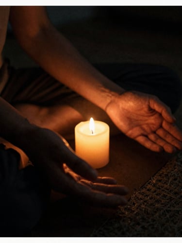 Low-key, warm candlelit photography of a practitioner's hands resting gently in a meditative pose, deep shadows, rich amber and charcoal tones, 35mm film.