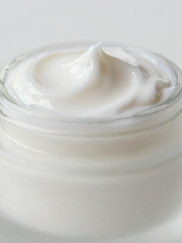 Macro product photography of a premium frosted glass jar reflecting soft morning light, showing a rich, milky white cream texture being swatched, clean minimalist composition, soft depth of field.