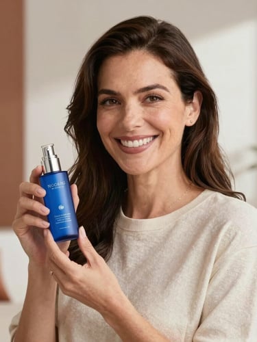 Medium portrait of Noemí Salvador smiling warmly in a bright, modern room with terracotta accents, holding a blue cosmetic bottle