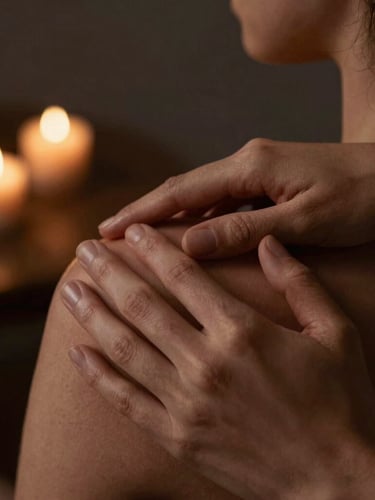 Close-up of warm hands-at-work therapy on a shoulder, low-key ambient candlelight, rich bronze and charcoal tones, shallow depth of field