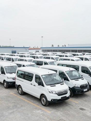 Wide-angle environmental shot of a clean wholesale holding lot filled with uniform white passenger vehicles under bright overcast daylight, desaturated cool tones, sharp focus