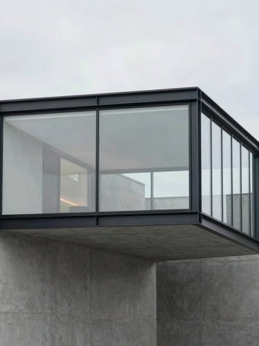 Modern glass and steel extension integrated into a minimalist concrete structure, overcast daylight, sharp focus, architectural photography, 35mm