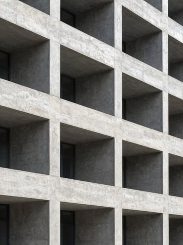 Structured architectural concrete facade of a modern research institution, sharp linear shadows, cool daylight, high contrast