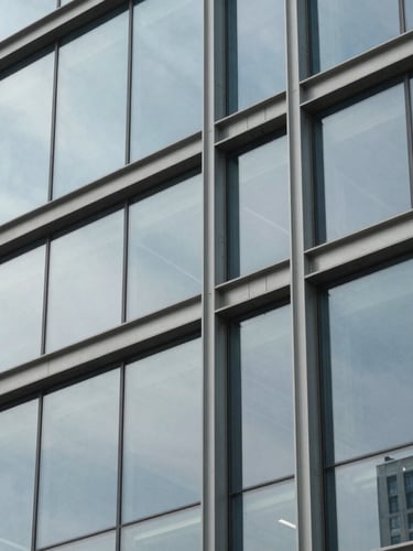 Macro architectural detail of a structured steel and glass facade, clean grid lines, high-contrast cool daylight, sharp focus on structural intersections.