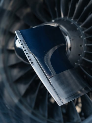 Macro shot of a high-performance aircraft turbine blade in crisp morning light, deep navy and silver metallic tones, sharp focus, premium corporate aviation photography