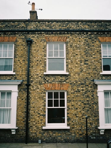 Straight-on architectural crop of a traditional UK brick terrace house facade, soft overcast British daylight, muted earth tones