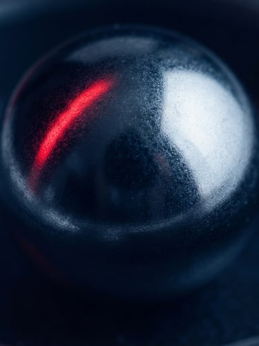 Macro photograph of a heavy-duty industrial chrome steel ball bearing, pristine metallic texture, deep navy blue shadows, sharp crimson red light reflection, high-contrast studio lighting.