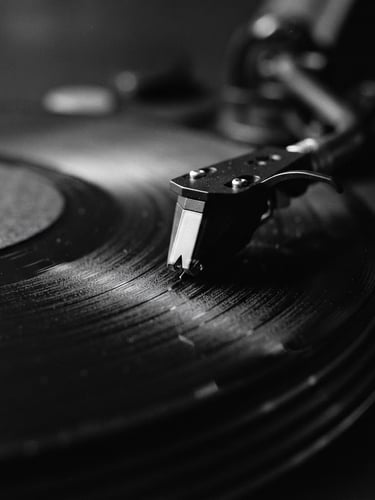 Macro photograph of a vinyl record groove spinning on a high-end turntable, moody low-light studio setting, high contrast black and white, 35mm