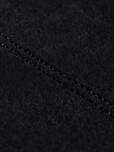 Macro close-up of heavy black cotton fabric texture, detailed stitching, soft moody studio lighting, high contrast monochrome, 35mm