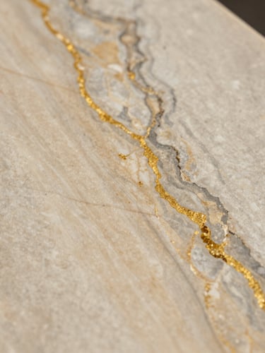 Close-up macro detail of a textured quartzite slab showing intricate gold and gray veins, soft diffused natural daylight, architectural material sample