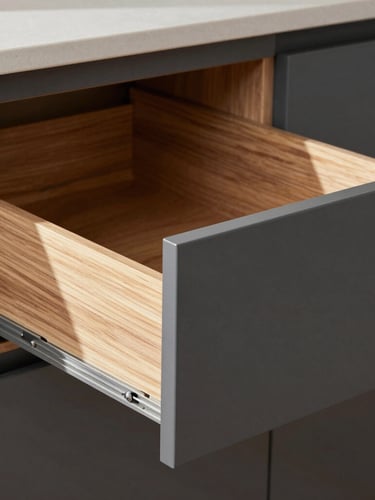 Straight-on architectural detail of a matte charcoal kitchen cabinet drawer sliding open smoothly, soft daylight hitting the walnut wood interior joint, 35mm lens, editorial style