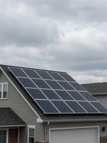 Wide environmental shot of a completed solar array installed on a two-storey Canadian suburban house, overcast diffused daylight, grey clouds above, dark roof shingles visible between panel rows, no people, shot from street level looking slightly upward, muted tones throughout