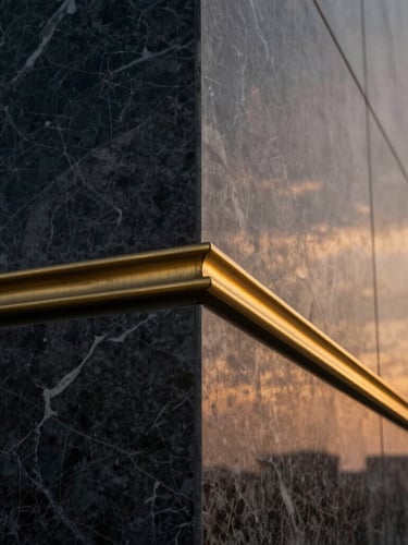 Close-up architectural photography of premium textured marble and brass joints, warm twilight light, high-contrast shadows