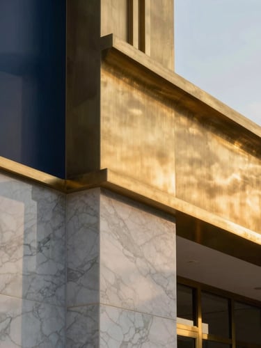 Close-up architectural detail of premium brushed brass and white marble textures, soft twilight shadows, elegant and structured composition.