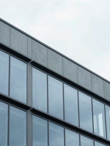 Architectural detail of a modern office building facade in CDMX, clean lines, reflection of overcast sky, minimalist 35mm photography.