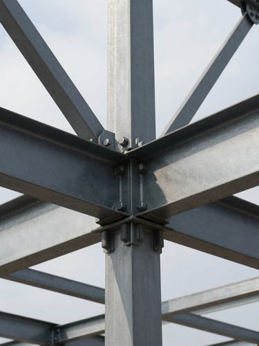 Industrial structural steel framing under overcast daylight, heavy bolts in a connection plate, crisp shadows on steel.