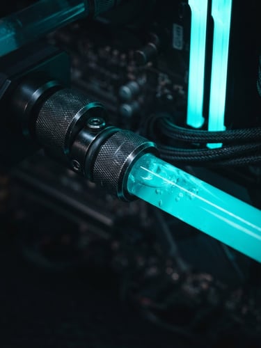 Extreme close-up of a glowing liquid-cooling loop inside a custom PC, neon-cyan coolant, metallic fittings, moody studio lighting