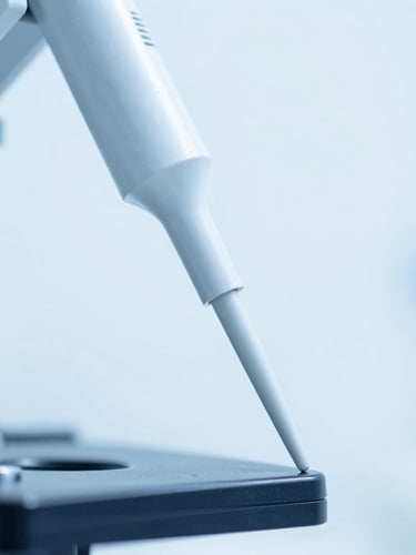 Macro close-up of high-tech molecular laboratory instrumentation with sterile pipette tips, cool blue lighting, high-key clinical white background.