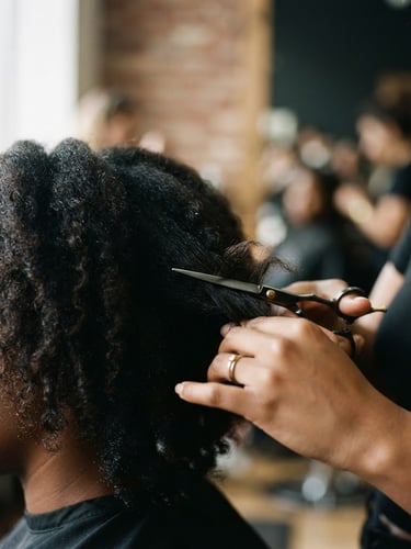 Editorial 35mm film photography of a sharp, clean scissor cut mid-action on dark textured hair, soft directional window light, muted black and gold tones, shallow depth of field.
