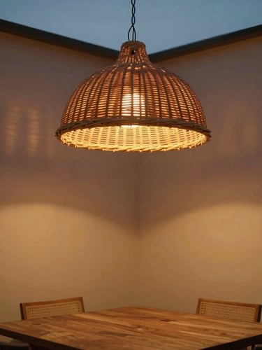 Medium architectural crop of a modern dining room at twilight, a large woven rattan dome ceiling pendant turned on, casting a warm low-glare amber glow on plaster walls, soft shadows, medium format film feel