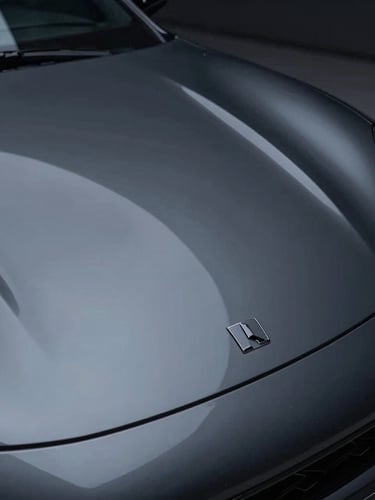 Sleek dark sports car hood showing sharp LED light reflection lines, high-contrast automotive detailing studio, macro lens, 35mm