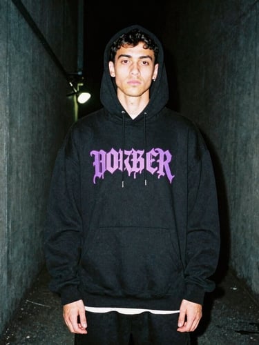 Gritty urban fashion photography, portrait of a young man wearing an oversized black streetwear hoodie with neon purple graphic print, standing in a dark concrete alley, high contrast, 35mm film grain