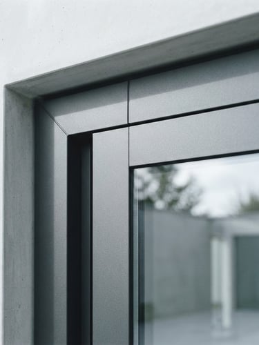 Symmetrical architectural close-up of a premium minimalist aluminium sliding door frame, corner joint showing millimeter precision, bright natural daylight reflecting off double-glazed glass, cool desaturated tones, 35mm lens.