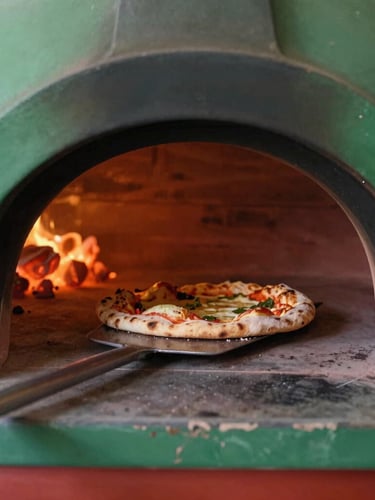 Close-up of a wood-fired oven interior, glowing embers, a rustic sourdough pizza being pulled out with a metal peel, warm side lighting, rich textures.