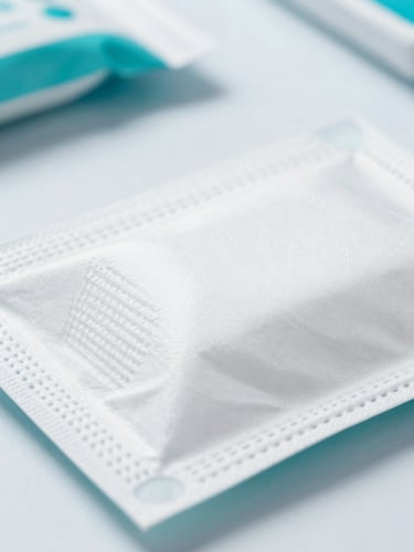 Macro close-up of high-quality medical disposables in sterile white packaging, bright clinical studio lighting, cool teal accents, sharp focus on product textures.