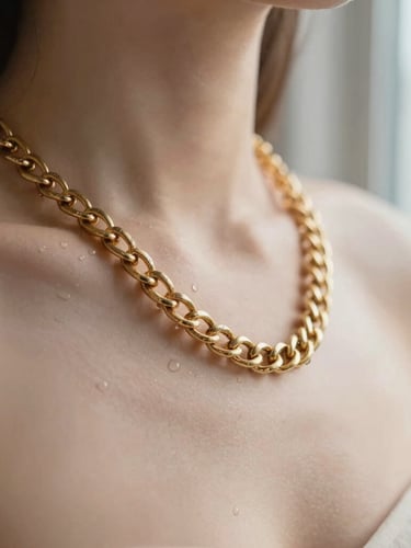 Macro crop of a heavy 18K gold chain draped over a collarbone, soft morning window light reflecting off the warm metallic surface, water droplets bead-gliding off the gold, shallow depth of field