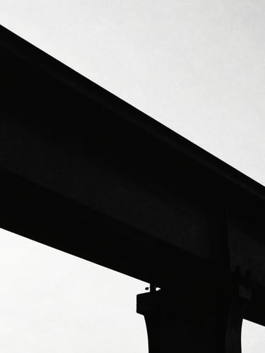 Stark high-contrast silhouette of a structural steel beam against a blinding white sky, deep black shadows, minimalist composition, raw texture, 35mm film grain