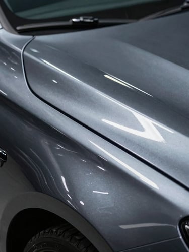 Extreme close-up of a flawless metallic car body line, sharp overhead linear LED light reflection showing perfect paint depth, deep obsidian color, high-contrast metallic details.