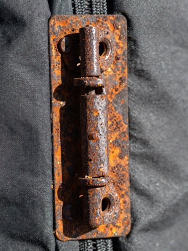 Macro close-up of a rusted, dismantled hinge from an outdoor gear item, showing corrosion and wear, hard direct natural light, high-contrast details, realistic wear and tear, 50mm lens