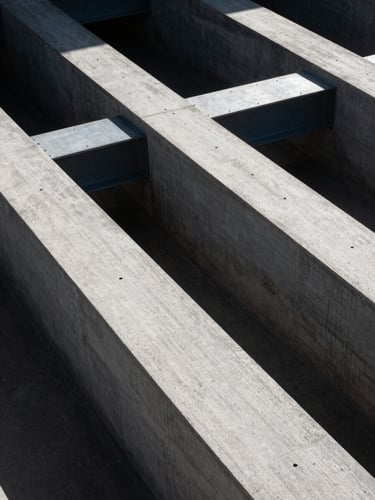 High-angle architectural abstract showing sharp geometric concrete lines and steel beams, high contrast daylight, dramatic shadows, cool-toned daylight.