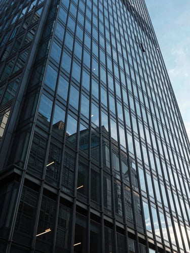 Extreme wide-angle architectural shot of a modern glass and steel skyscraper facade, deep blue sky reflection, high-contrast geometric shadows, daylight.
