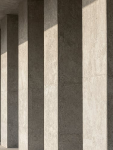 A close-up of clean, minimalist concrete architectural pillars in soft, diffused morning light, creating a sense of structural order and stability.
